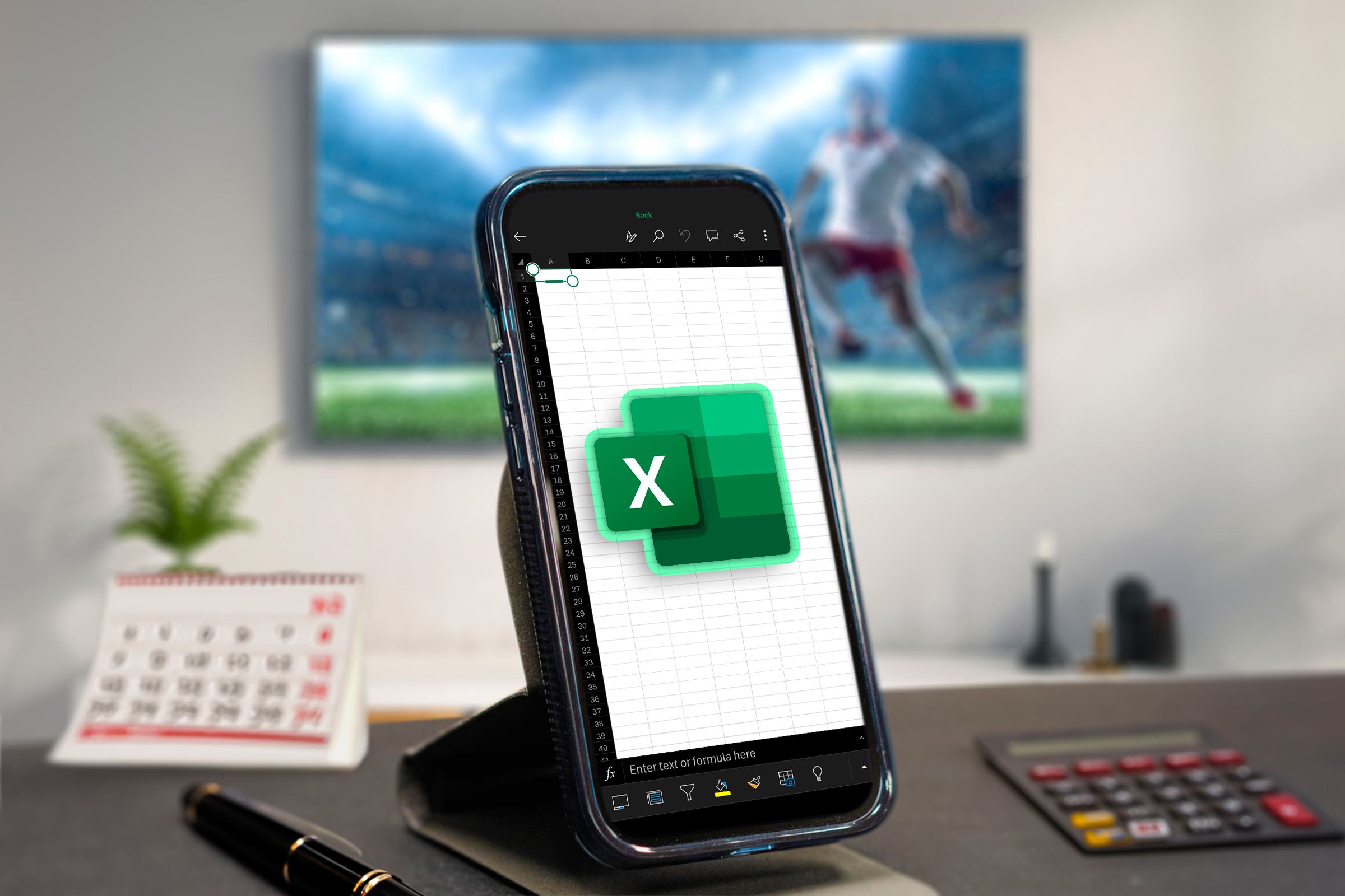 A phone with Excel open, some office objects around and a TV in the background.