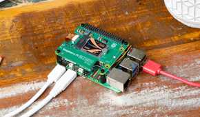 Raspberry Pi computer on a wooden surface with cables connected.
