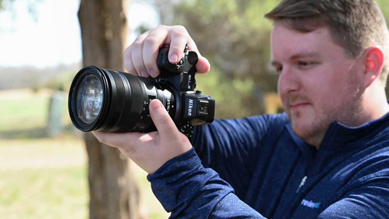 Pessoa tirando fotos de um parque com uma câmera Nikon