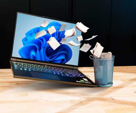 A windows 11 laptop with some files being dumped into a trash can.
