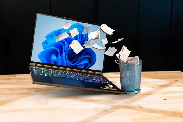 A windows 11 laptop with some files being dumped into a trash can.
