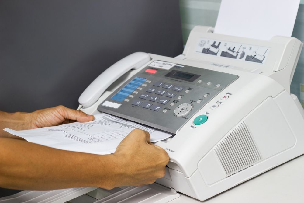 A man using a fax machine in an office.