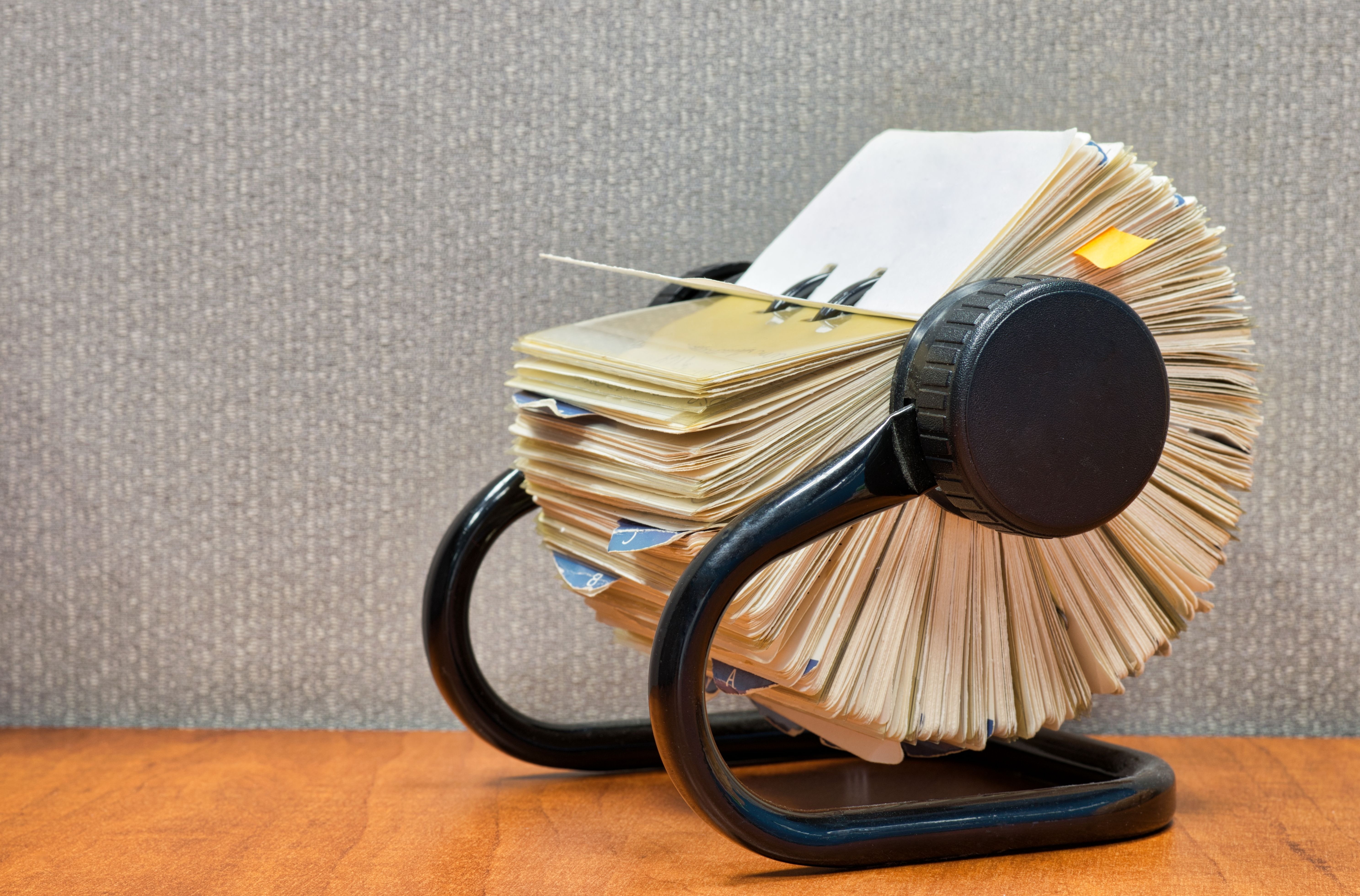 Rolodex file organizer sitting open on an office desk, angled view with gray cubicle partition behind.