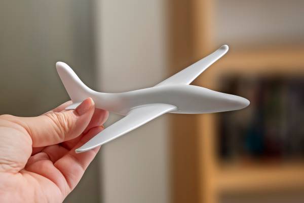 A hand holding a 3D printed plane.