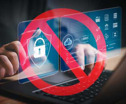 Hands typing on a laptop with a red prohibition sign over security icons, indicating a restriction on digital access.