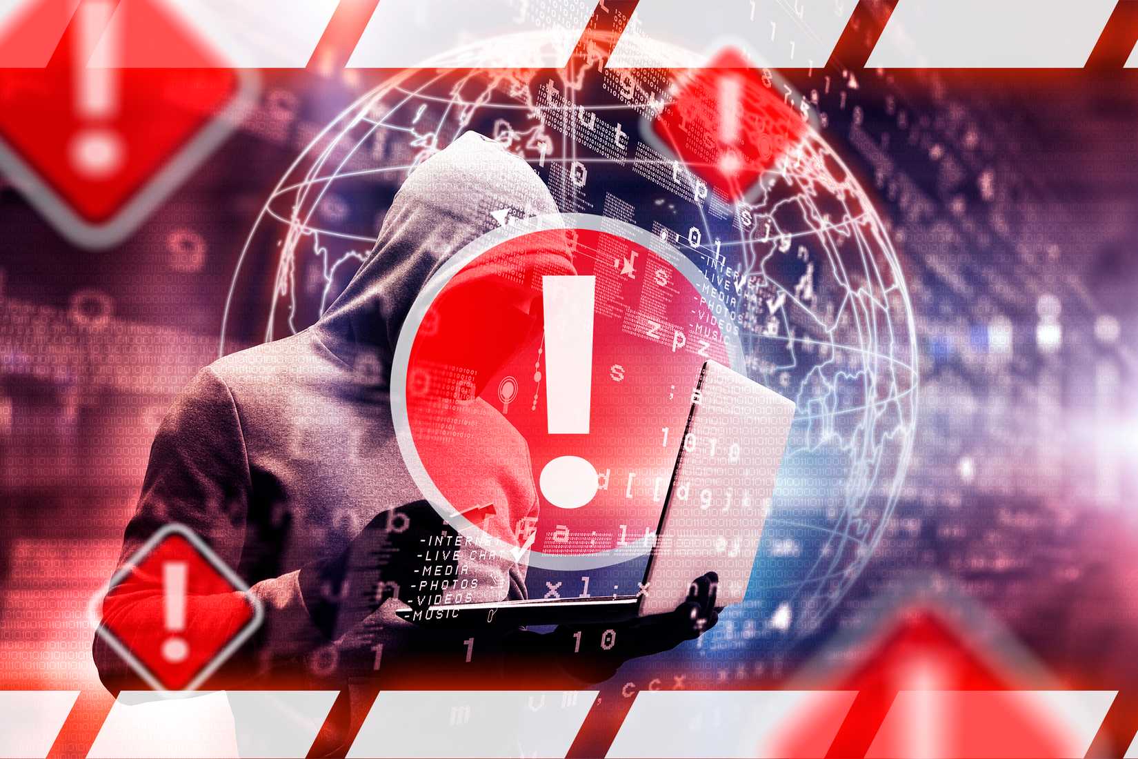 A hooded person hacking data into a laptop with several warning signs nearby.
