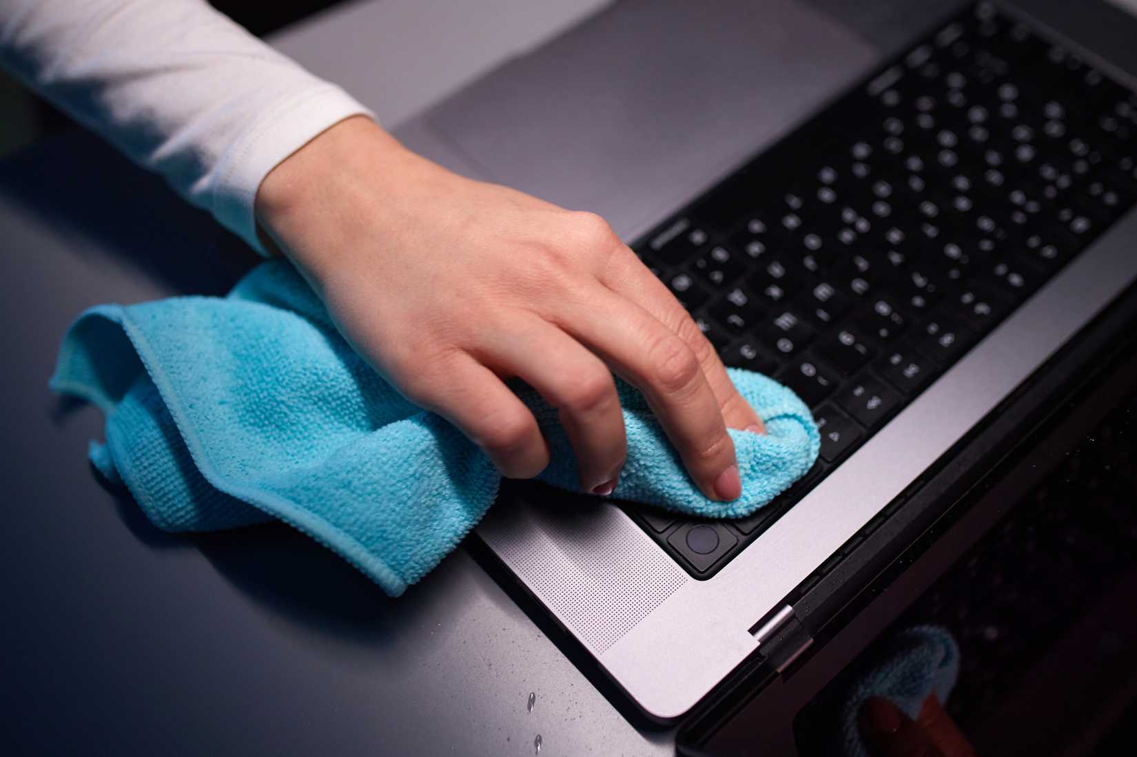 A person cleaning a MacBook Pro with a microfiber cloth.
