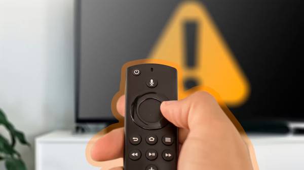 hand holding a fire TV remote with a TV in the background. 