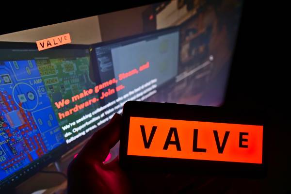 Person holding smartphone with logo of Valve on screen.