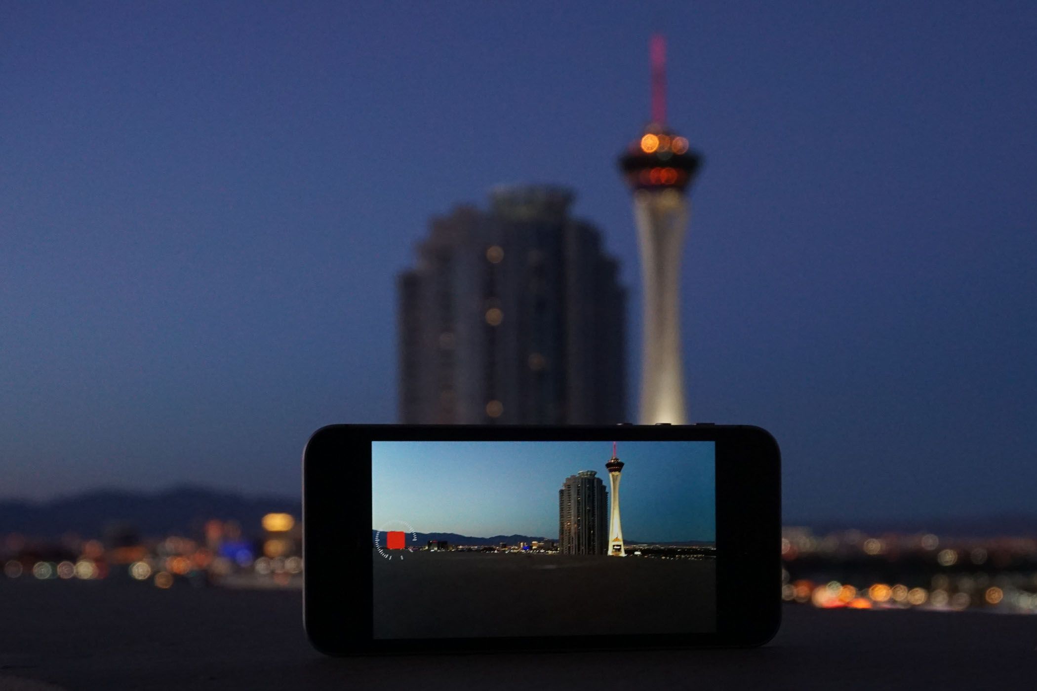 A smartphone on a mini tripod taking a long-exposure photo of the Las Vegas skyline.