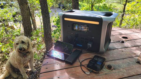 The Anker 757 power station charging devices on a wood table next to a dog.