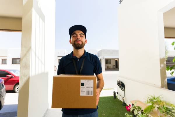 A delivery man standing in front of a smart doorbell camera.