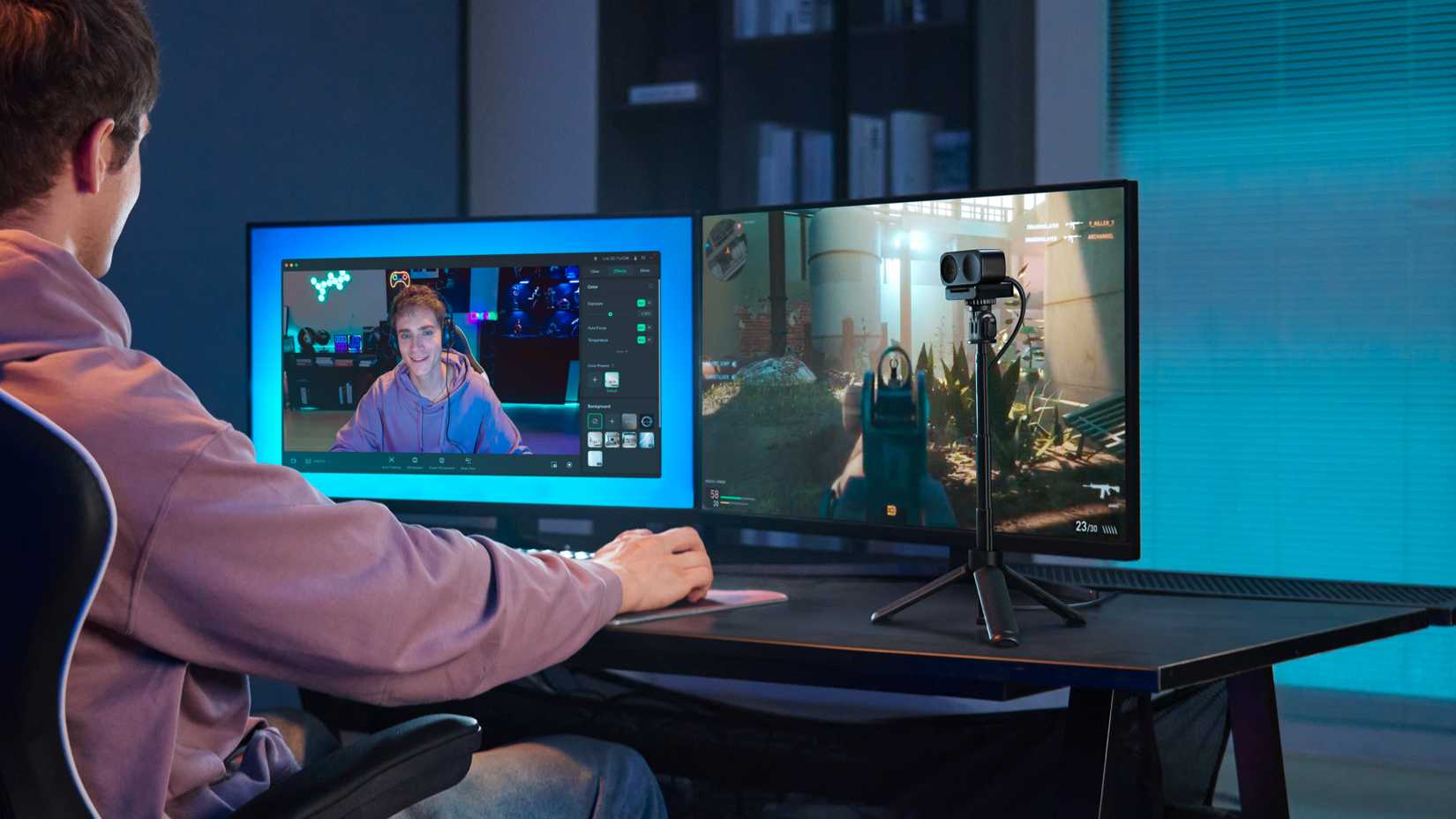 Young msn in s room live-streaming gaming on his computer using an Insta Link 2 webcam mounted on a mini tripod.