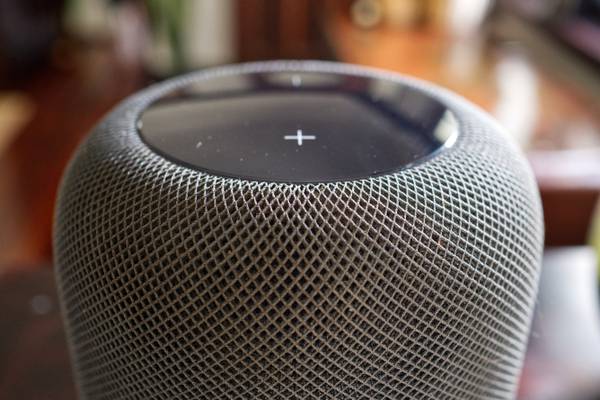 A first-generation gray HomePod speaker in a living room.