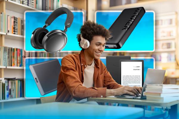 A young man studying in a library with his laptop and some gadgets in the background.