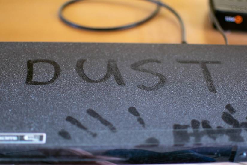 A very dusty DVD player with the word dust written on it in its own dust.