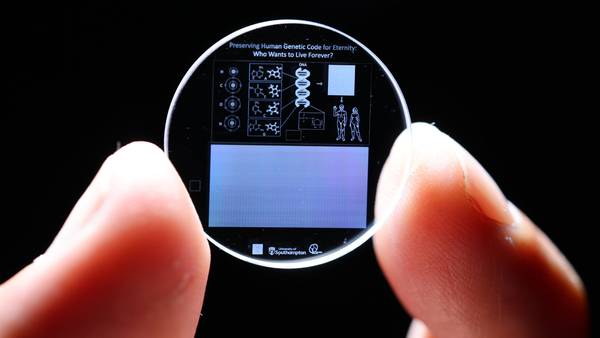 The 5D crystal holding the human genome held between thumb and forefinger.