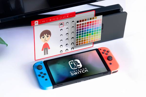 A Nintendo Switch on a shelf with a Mii Maker next to it.