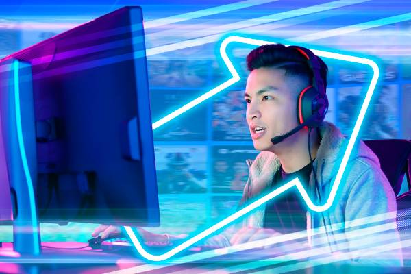 A young man wearing a headset playing games on his PC.