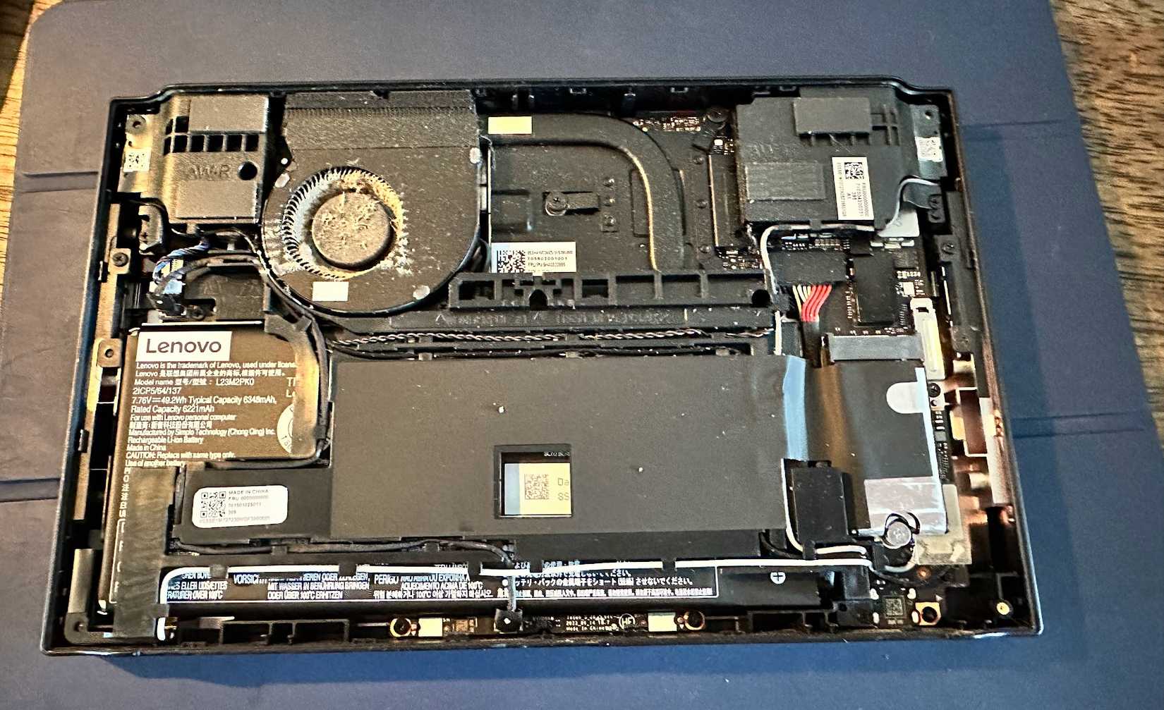Lenovo Legion Go with back plate removed, showing heavy dust inside the cooling fan.