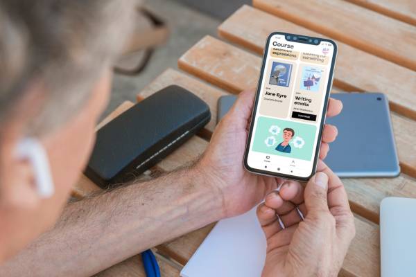 Man holding a phone with the Promova language app on the screen. 