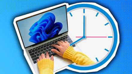 A person using a laptop with Windows 11 and a clock beside it.