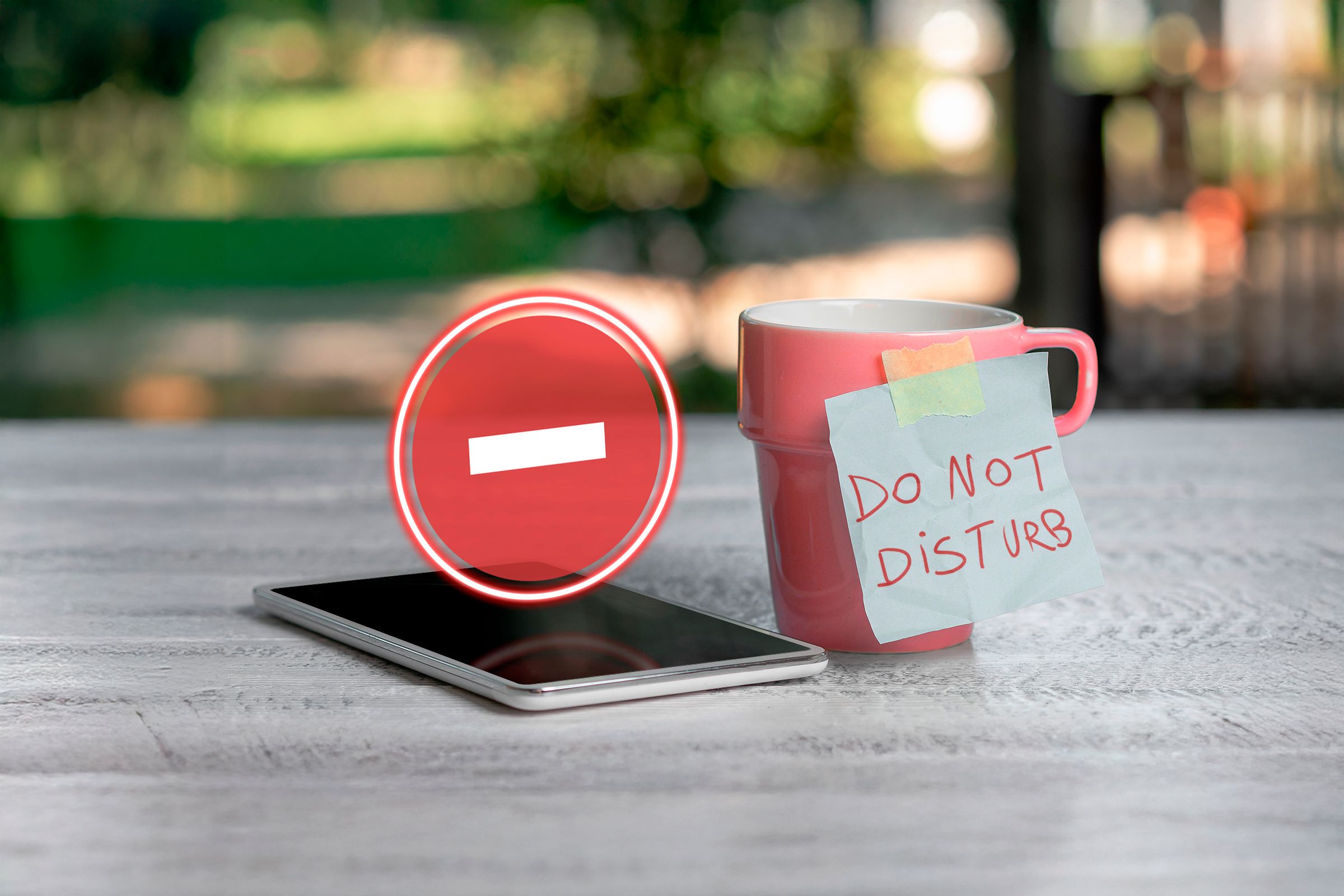 A phone with the Do Not Disturb icon floating above the screen and a mug next to it with the label 