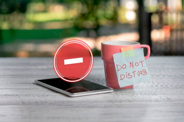 A phone with the Do Not Disturb icon hovering above the screen and a mug next to it labeled 'Do Not Disturb'.