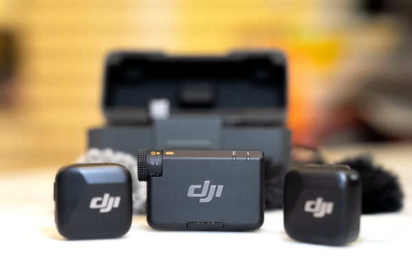 The DJI Mic Mini kit displayed on a table. One transmitter is visible in the center of the image with two of the system's microphones next to it. 