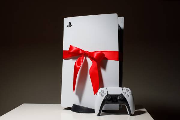 PlayStation 5 against a dark background with a red ribbon around it.