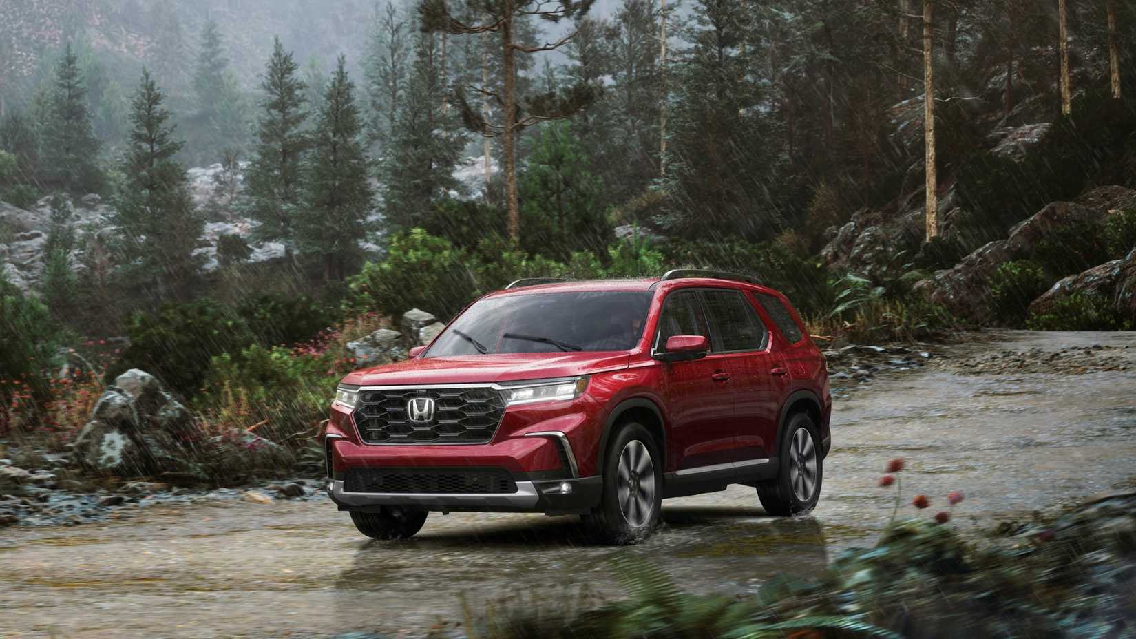 Front 3/4 view of red 2023 Honda Pilot Elite driving in the rain.