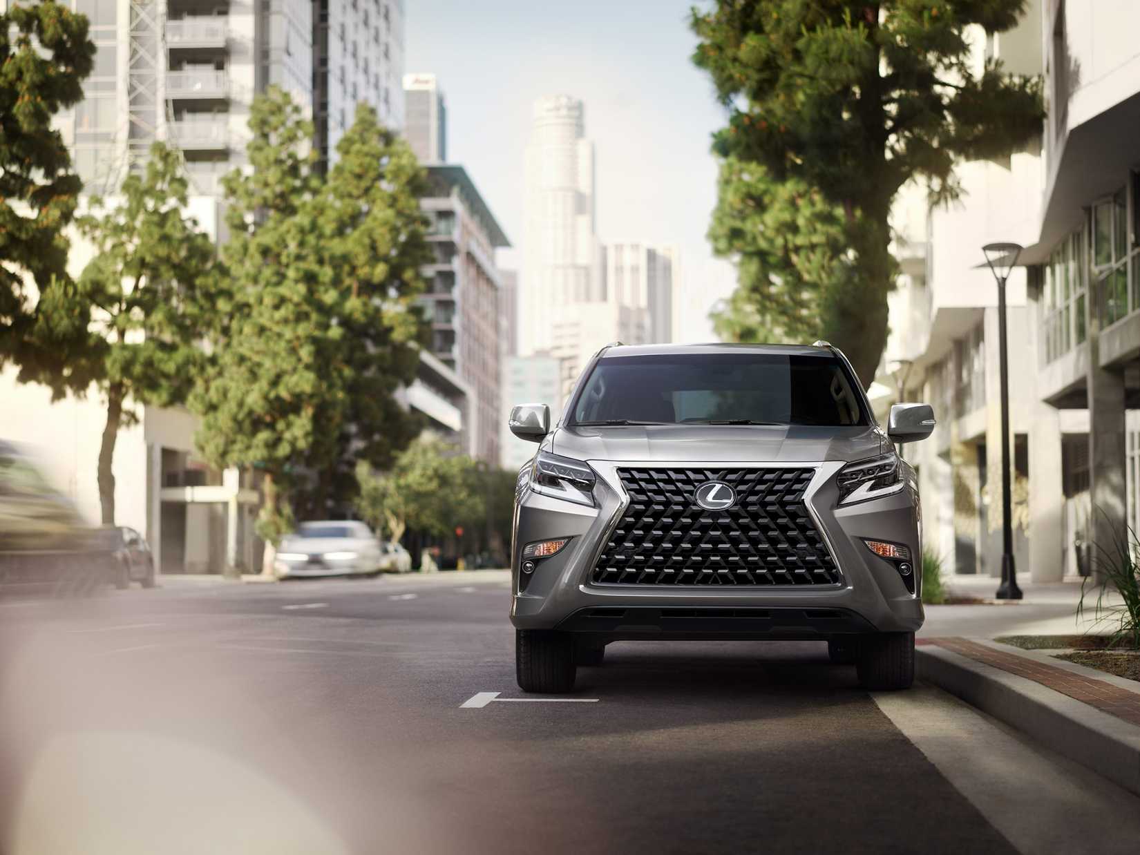 A silver Lexus GX 460 parked on a street alongside a sidewalk in a city.