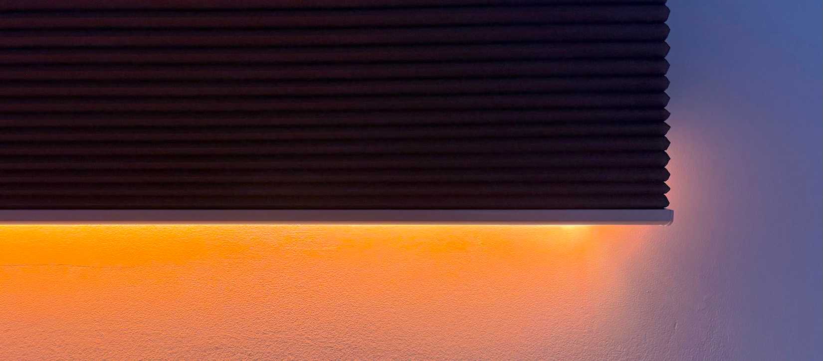 A smart blind with smart lights that provide a mix of blue and orange mood lighting.