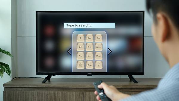 A smart TV with a T9 keyboard layout on the screen in a retro style.