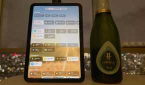 An iPad smart home control panel next to a bottle of champagne.