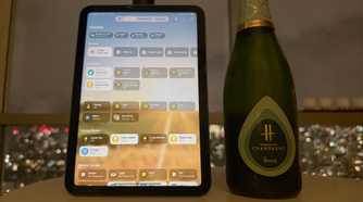 An iPad smart home control panel next to a bottle of champagne.