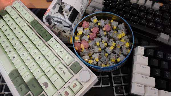 Several keyboards, mechanical keyboard switches, and keycaps from Temu on a desk.