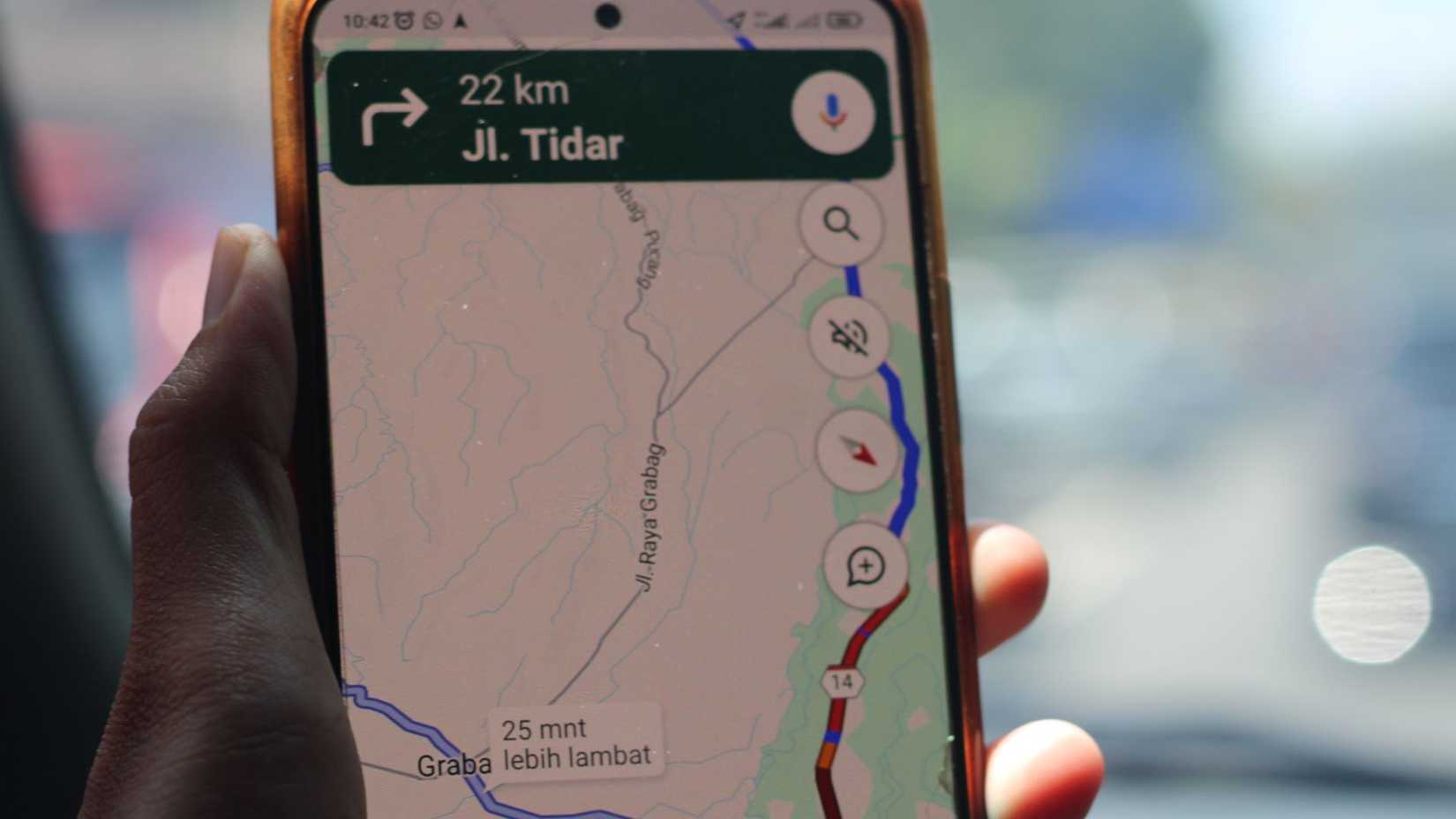 Uma pessoa em um carro segurando seu smartphone exibindo informações de trânsito em tempo real do Google Maps.