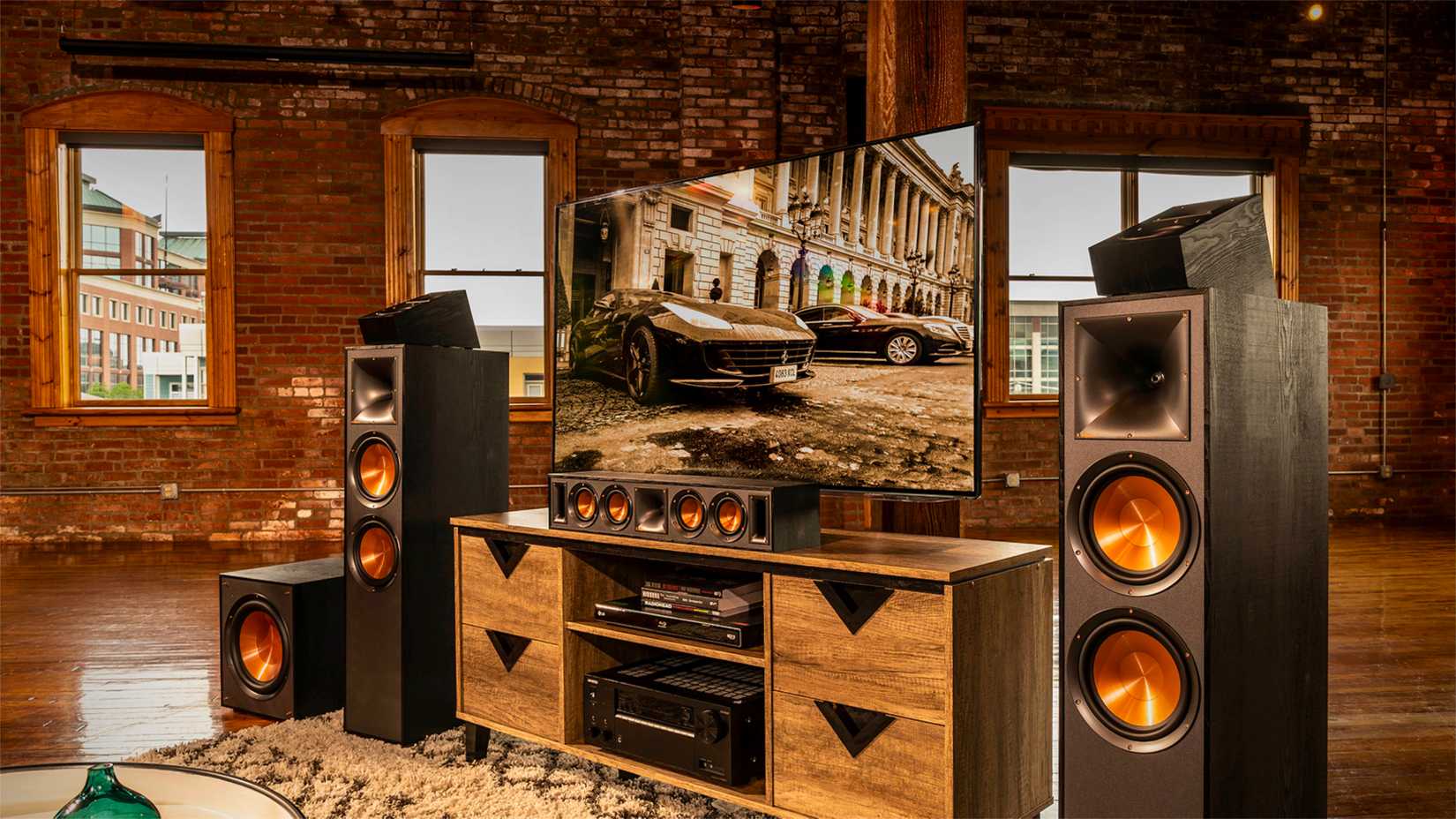 A home theater setup with a lot of wood texture with a television, two speakers, and a receiver.