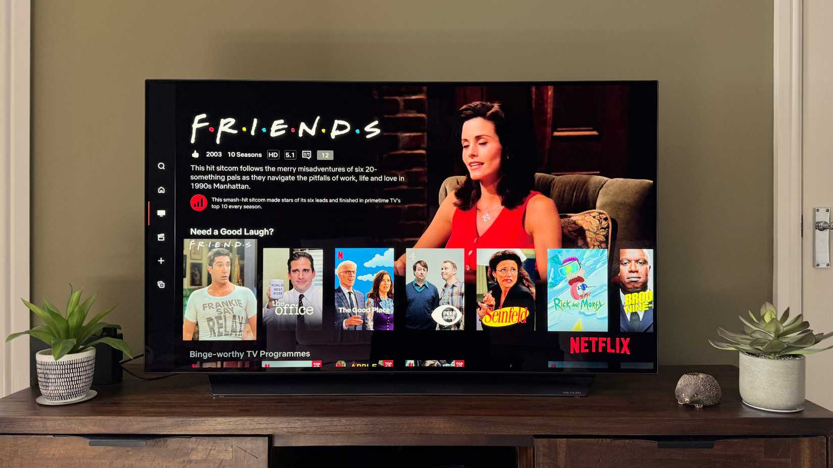 4K TV in a green living room showing Friends and other comfort shows on Netflix.