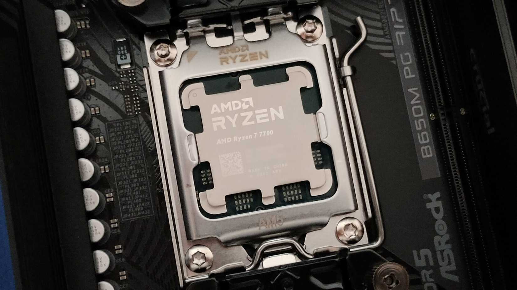 Close-up of AMD Ryzen 7 7700 CPU in AM5 socket and ASRock B650M PG RIPtide motherboard.