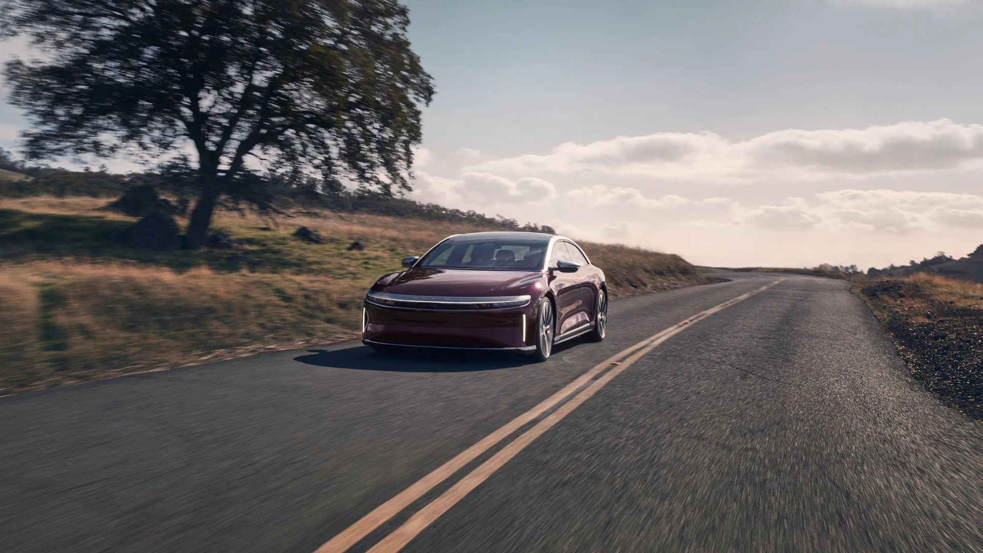 Front view of red Lucid Air Grand Touring driving on a country road.