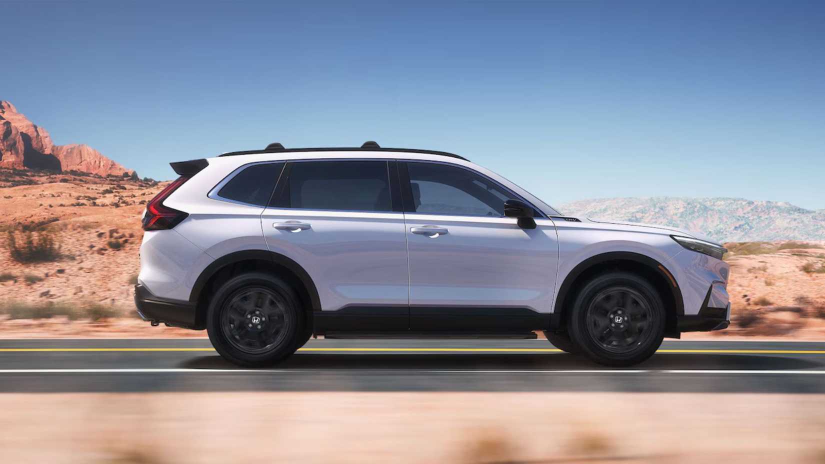 White Honda CR-V Hybrid driving on a road through the desert.