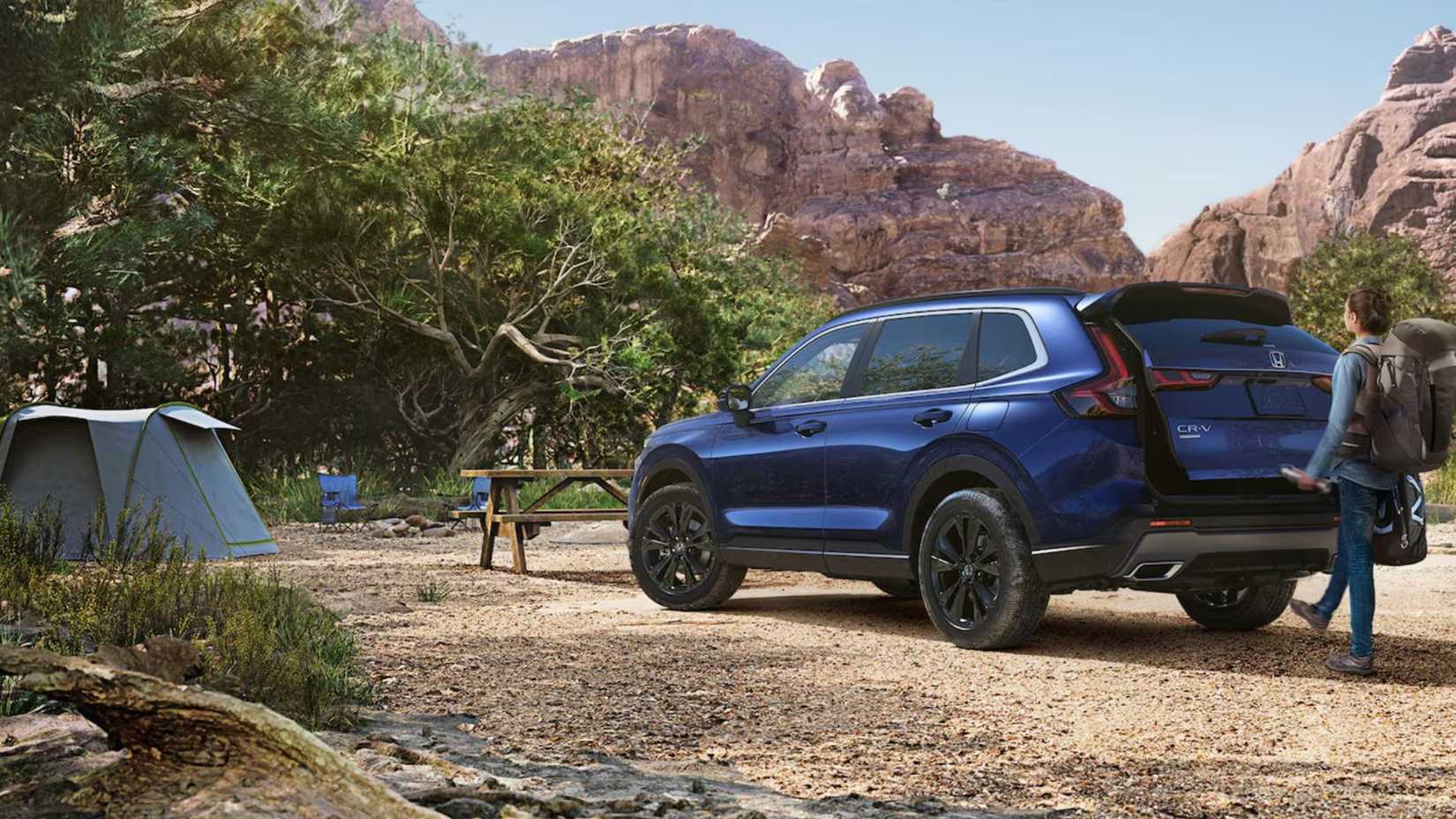 Rear of a Honda CR-V Hybrid at a campsite with a person opening the trunk.