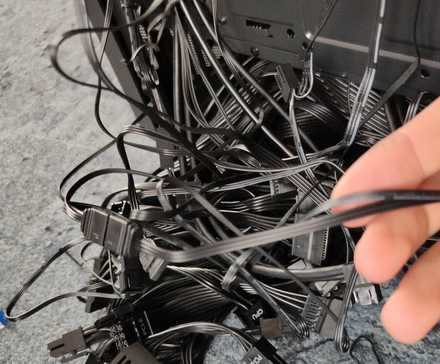 Neorganizované čierne počítačové káble trčiace z počítačovej skrinky.