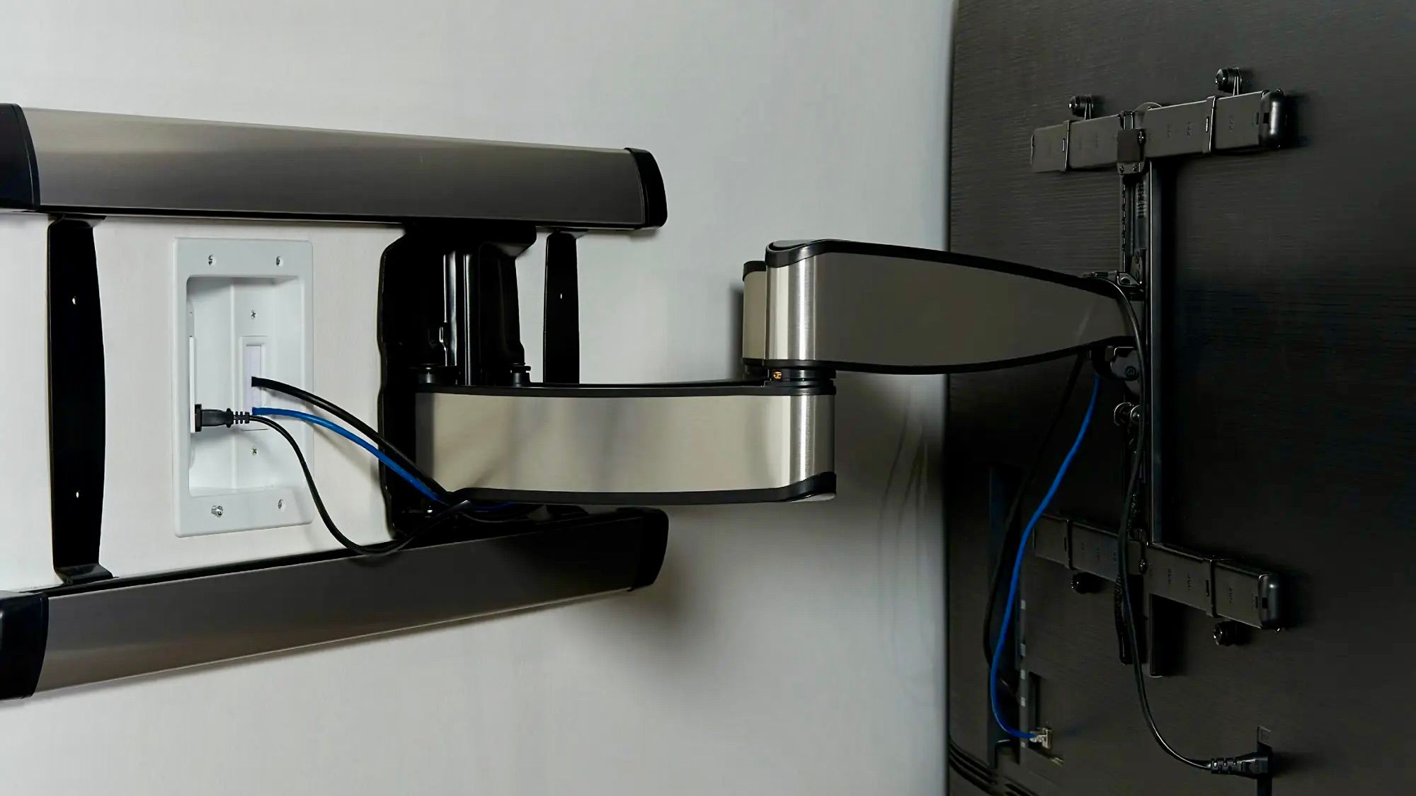 A Sanus in-wall power kit installed behind a wall-mounted TV.