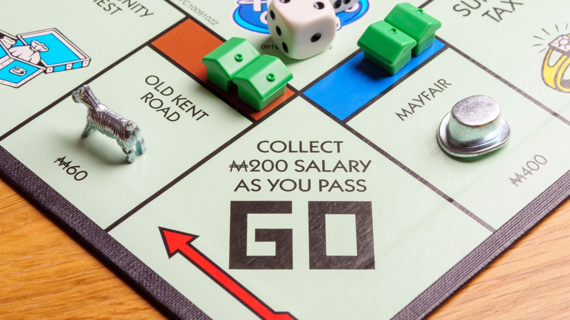 Close up of playing pieces passing Go square and being paid a salary on a Monopoly board game