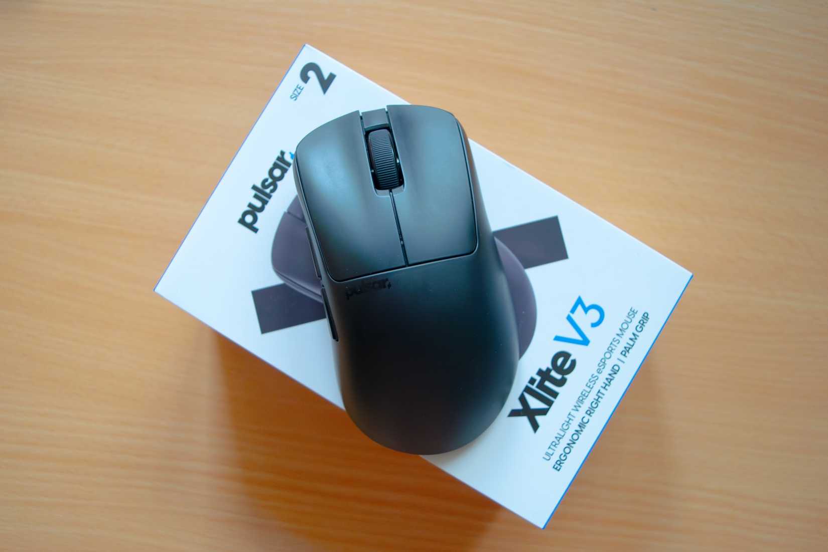 A Pulsar Xlite V3 mouse lying on top of the box it comes in. 