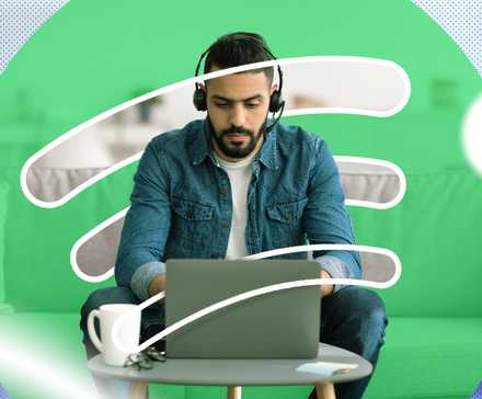 Серьёзный мужчина работает за ноутбуком в наушниках с логотипом Spotify на фоне.