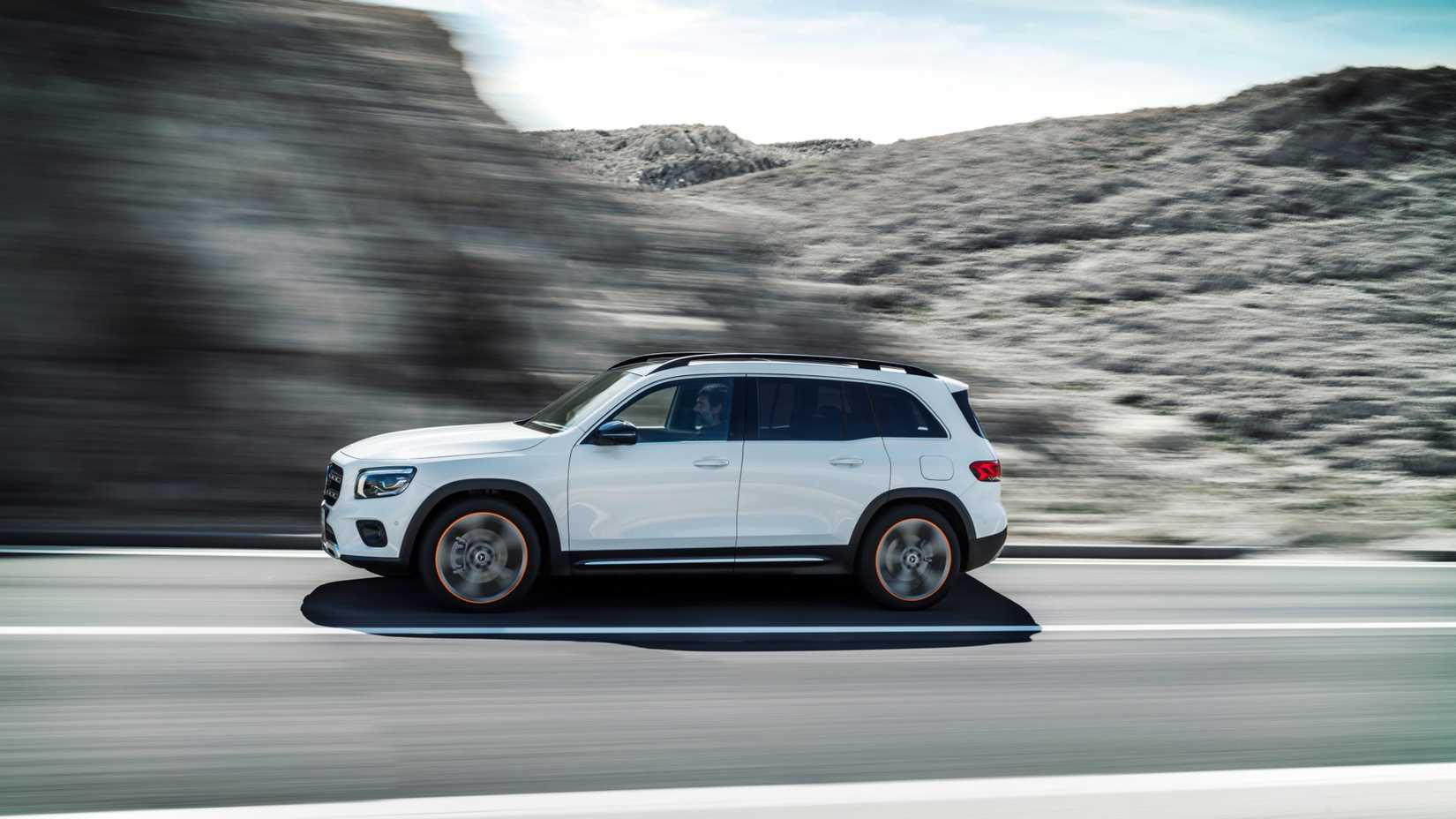 Dynamic side profile shot of a white 2021 Mercedes-Benz GLB driving on a country road.